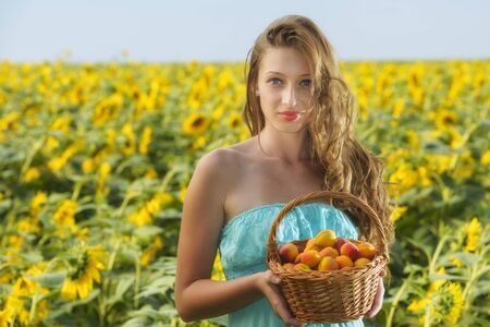 young woman in sunflower chain with a basket of fruitの写真素材