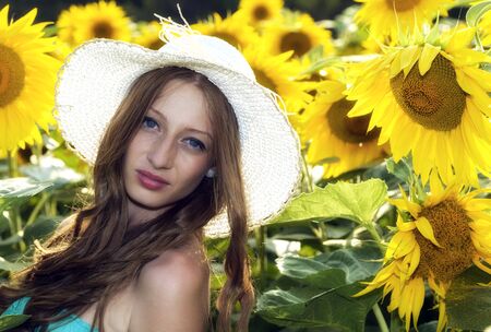 young woman on blooming sunflower field in summerの写真素材