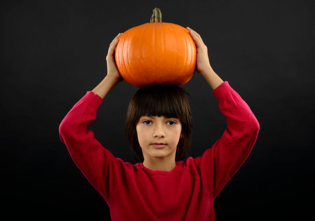 Portrait of little boy wearing halloween costume with pumpkin on black  backgroundの写真素材