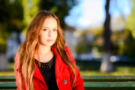 Beautiful elegant woman standing in a park in autumnの写真素材