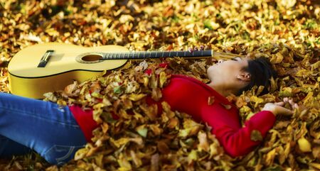 Beautiful brunette guitar player girl in the forestの写真素材