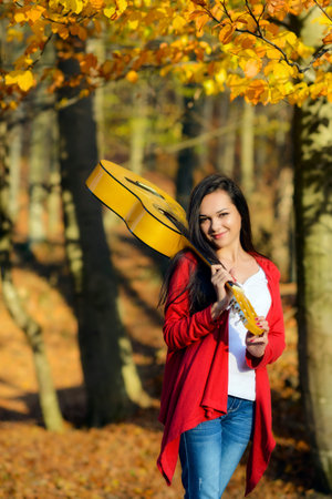 Beautiful brunette guitar player girl in the forestの写真素材