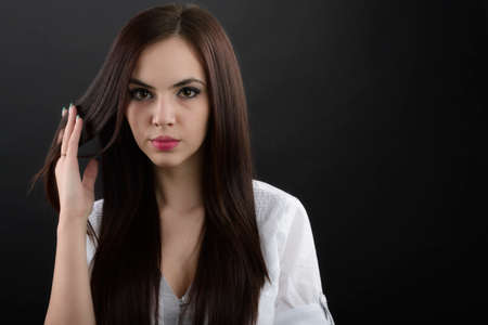 Young attractive woman with long black hair on black background の写真素材
