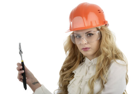 A woman with a helmet with a pipe wrench and safety glassesの写真素材