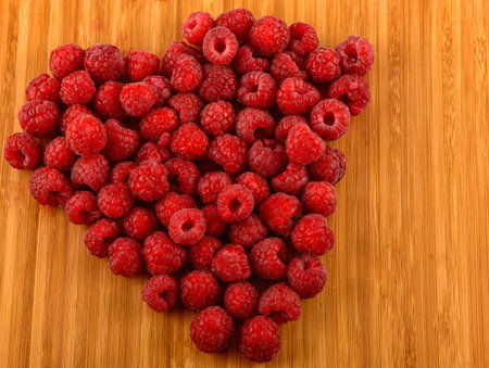 heart shaped raspberry isolated on wood