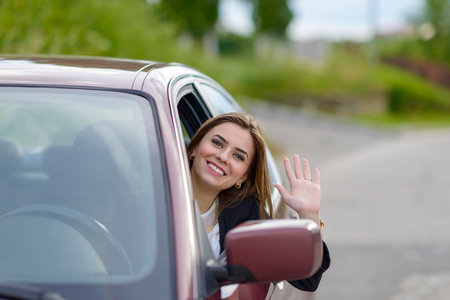 Young woman waving from car window