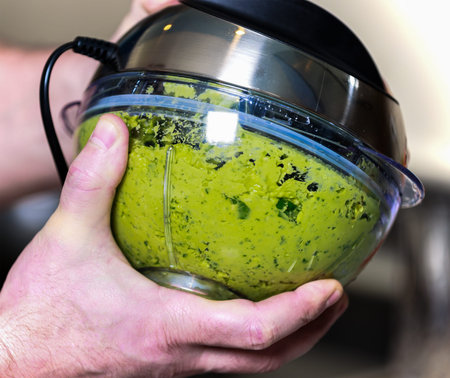 Close-up of a chef using a hand blender to make pesto