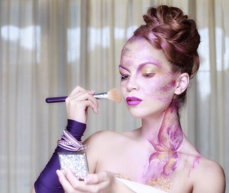 Beautiful woman with makeup brushes near her faceの写真素材