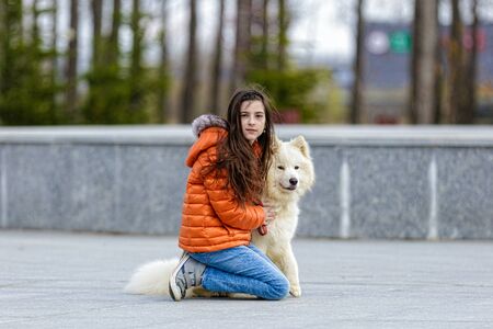 A little beautiful girl with her pet dog outdoors in parkの写真素材