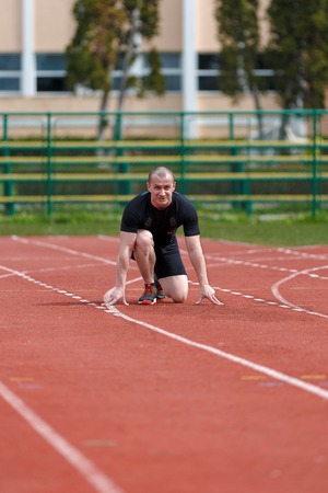 muscular athlete is at the start of the treadmill at the stadiumの写真素材