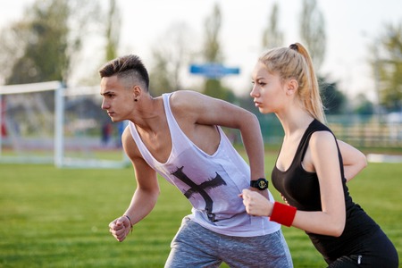 Young sport couple in starting position prepared to compete and runの写真素材
