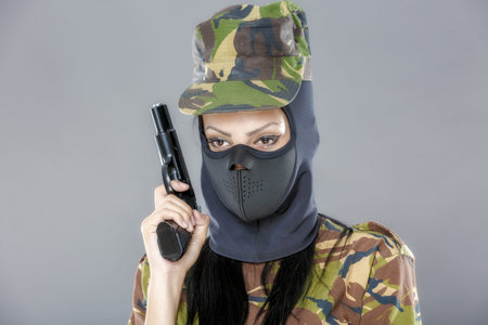 Female soldier in camouflage uniform with weapon isolated on gray background