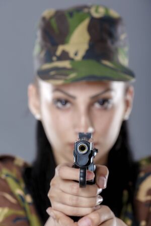 Female soldier in camouflage uniform with weapon isolated on gray backgroundの写真素材