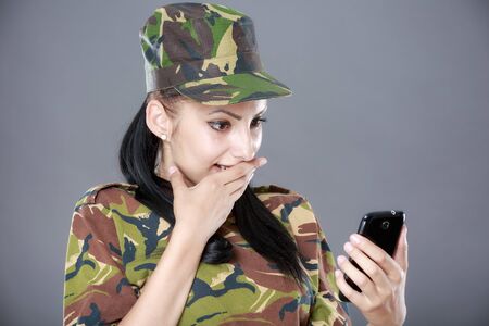 happy woman soldier looks at a mobile phoneの写真素材