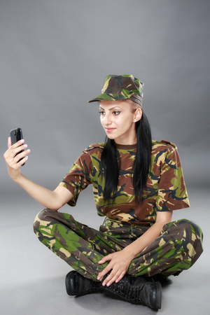 happy woman soldier looks at a mobile phoneの写真素材