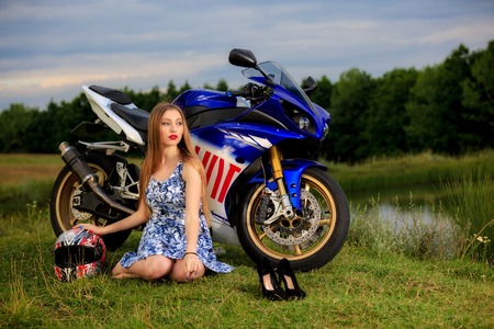 beautiful young woman with a motorcycle speed in natureの写真素材
