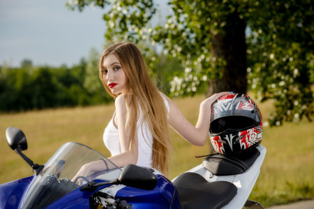 beautiful young woman with a motorcycle speed in nature