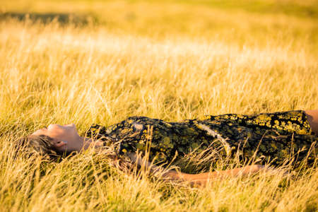 woman lies down in the grass yellowの写真素材