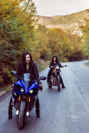 two beautiful women passionate about motorcycles, posing in natureの写真素材