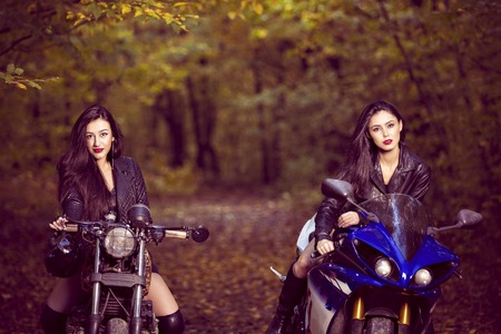 two beautiful women passionate about motorcycles, posing in natureの写真素材