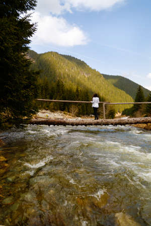 Beautiful woman tourist on a wooden bridge over a riverの写真素材