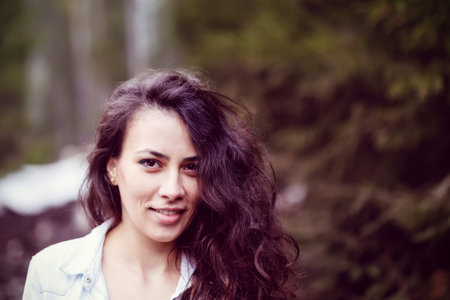 Closeup of a beautiful hispanic woman outdoor near a pine forest and mountainsの写真素材