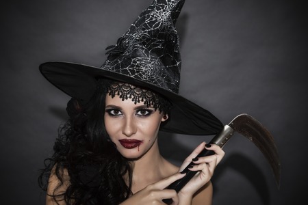 closeup portrait of woman with bloody knife in her hand in the darkの写真素材