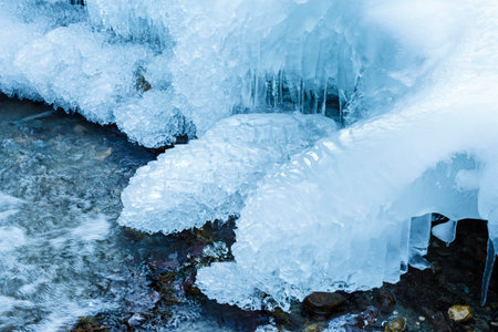 Closeup of a frozen mountain river flowing through icy rocks