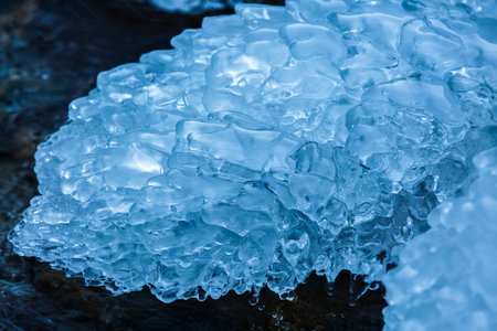 Closeup of a frozen mountain river flowing through icy rocksの写真素材