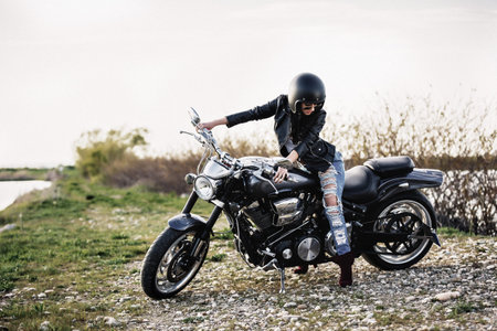 Beautiful motorcycle brunette woman with a classic motorcycle (cinema bleach bypass effect)