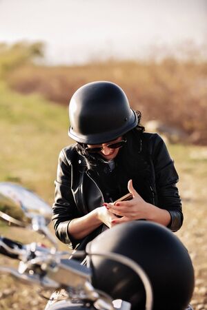 Beautiful motorcycle brunette woman with a classic motorcycle (cinema bleach bypass effect)の写真素材