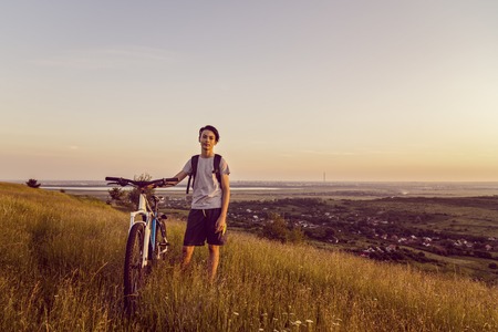 Young boy with a bicycle on a hillの写真素材