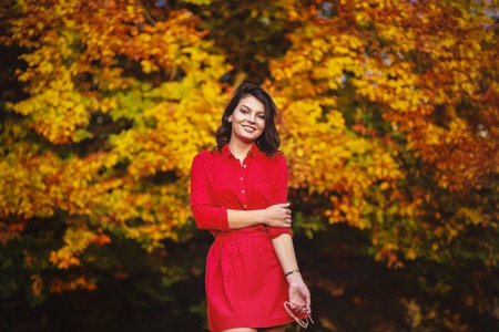 Beautiful young brunette enjoys a sunny day of autumn in natureの写真素材