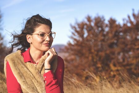 Beautiful young brunette enjoys a sunny day of autumn in natureの写真素材