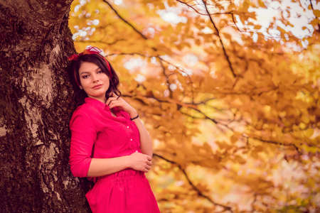 Beautiful young brunette enjoys a sunny day of autumn in natureの写真素材