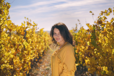 Beautiful young brunette enjoys a sunny day of autumn in natureの写真素材