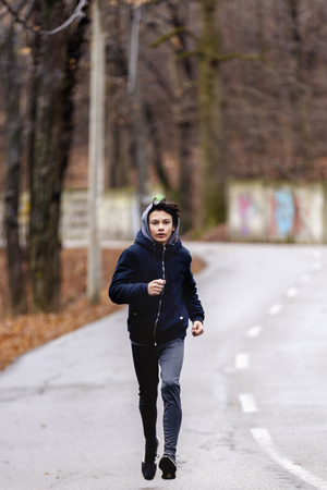 young man running in the park during the rainの写真素材