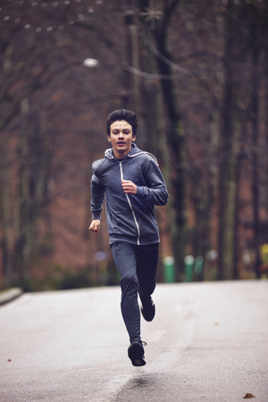 young man running in the park during the rainの写真素材