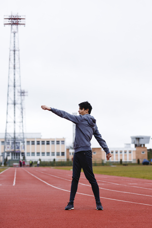 young sportsman makes exercises on a running trackの写真素材