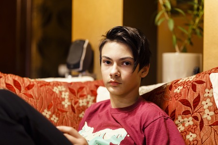 a boy sitting on the couch and playingの写真素材