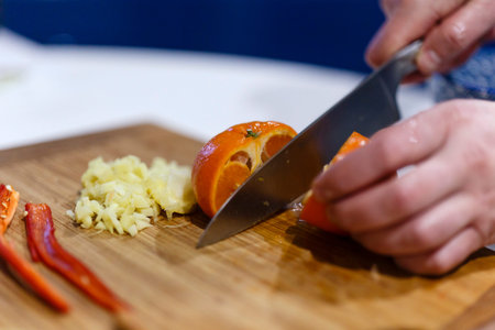 hands of a man who cuts citrus on a wooden hoe