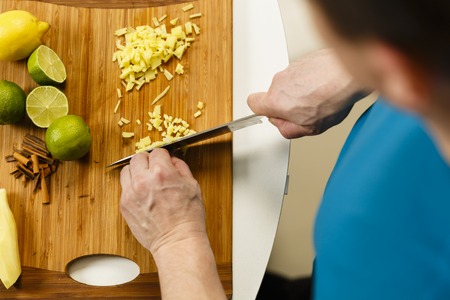 Man chopping ginger on a wooden board, closeup shotの写真素材