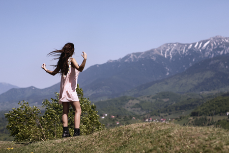 A beautiful woman in the dress enjoys the view of a mountain landscapeの写真素材