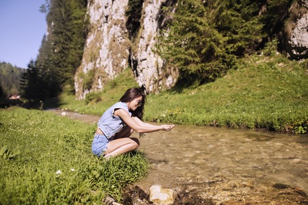 A beautiful tourist enjoys nature next to a mountain riverの写真素材
