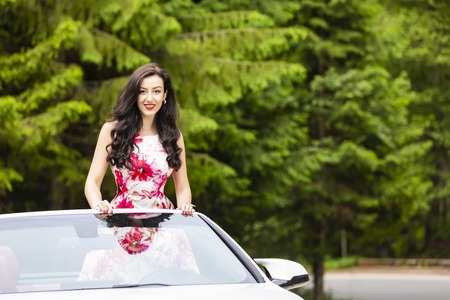 Fashion portrait of young woman in elegant dress outdoor in cabriolet carの写真素材