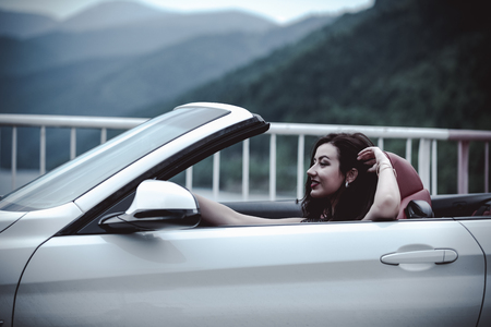 Fashion portrait of young woman in elegant dress outdoor in cabriolet carの写真素材