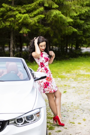 Fashion portrait of young woman in elegant dress outdoor in cabriolet carの写真素材