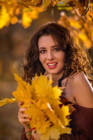 A portrait of a beautiful young woman in an autumn forest. Lifestyle, autumn fashion, beauty.
