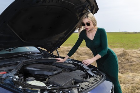 Young woman with heels repairing her broken carの写真素材