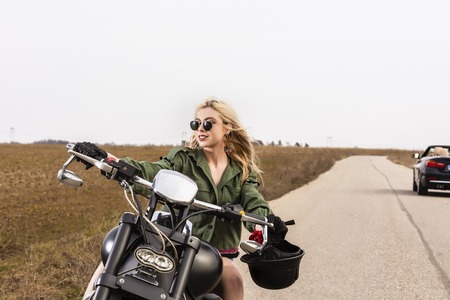 A beautiful young woman sitting on a black and chrome motorbikeの写真素材
